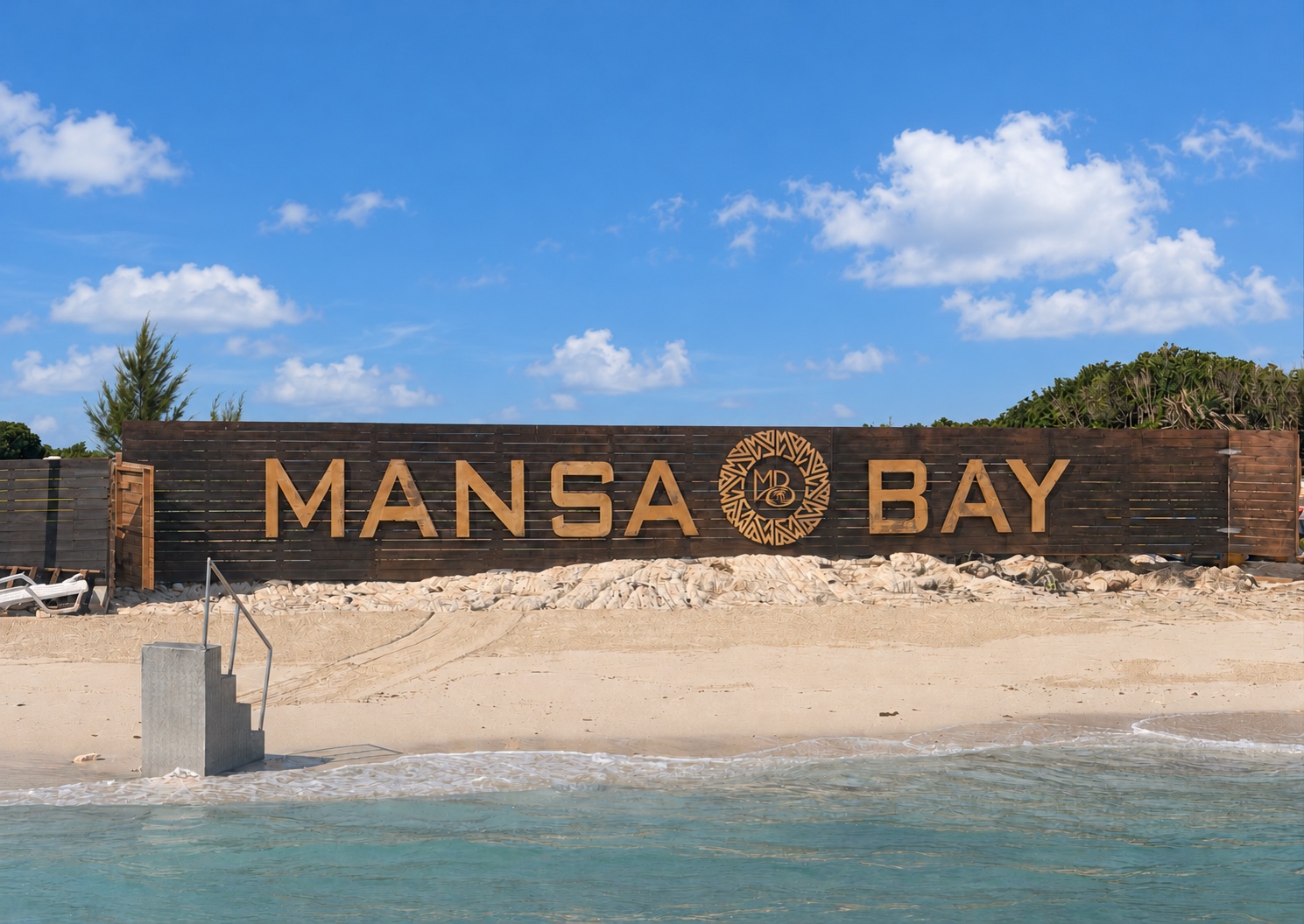 Mansa Bay beach sign beside the shoreline on Athol Island under a sunny blue sky